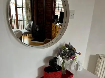 a vase of flowers on a table with a mirror at 2 Bed Duplex Penthouse Apartment by Mathew Street Sleeps 6 in Liverpool