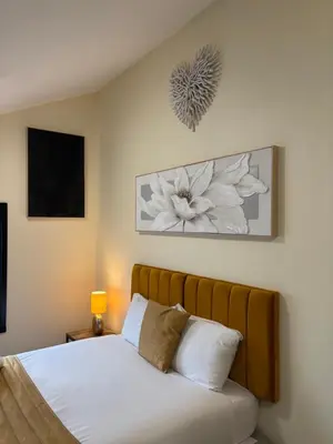 a bedroom with a bed with white sheets and flowers on the wall at York Street Studios in Liverpool