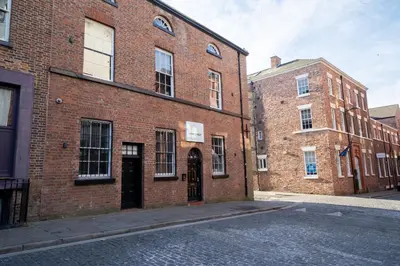 a large brick building with a door on a street at York Street Studios in Liverpool