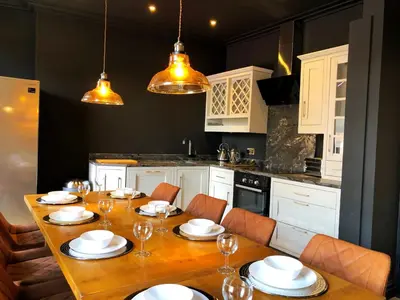 a kitchen with a wooden table with chairs and white cabinets at The Residence Sasco Apartments in Blackpool