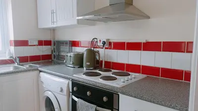 a kitchen with a stove and red and white tiles at Bright, Comfortable Home, Convenient for City Centre in Liverpool