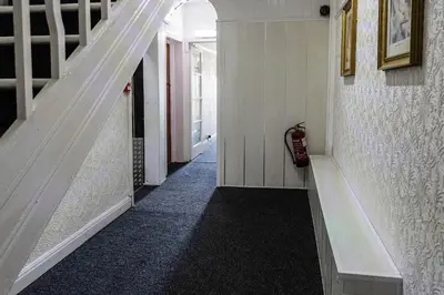 a hallway with a white staircase with a black carpet at Harlands Hotel in Blackpool