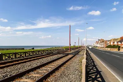 a road with a train track next to the ocean at Harlands Hotel in Blackpool
