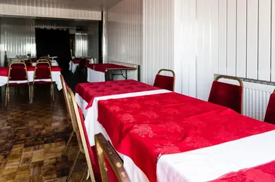 a room with two beds with red sheets and tables and chairs at Harlands Hotel in Blackpool