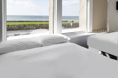 two beds in a room with a view of the ocean at Harlands Hotel in Blackpool