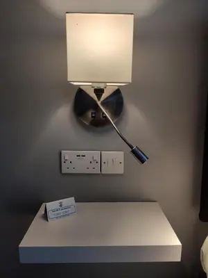 a lamp on a table with a light on a wall at Q Accommodation in Blackpool