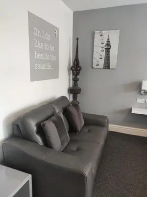 a leather couch in a living room with a sign on the wall at Q Accommodation in Blackpool