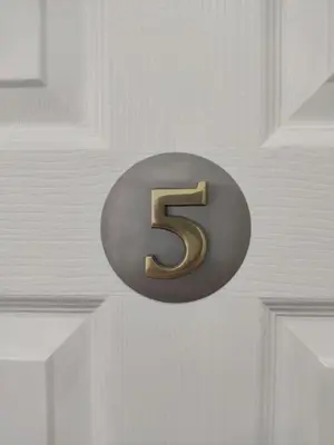 a metal number sign on a white door at Q Accommodation in Blackpool