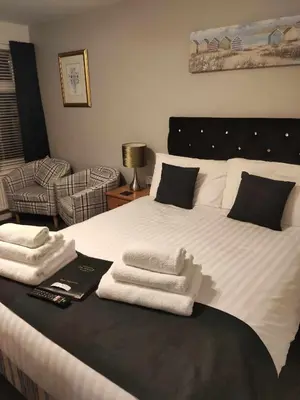 a bedroom with a large white bed with towels on it at Q Accommodation in Blackpool