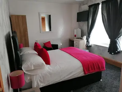 a bedroom with a bed with red pillows and a window at Birchhouse in Blackpool