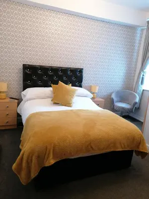 a bedroom with a large bed with a yellow blanket at Birchhouse in Blackpool