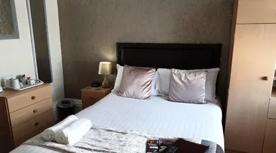 a bedroom with a bed with white sheets and pillows at Hilbre Hotel in Blackpool