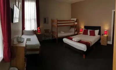 a hotel room with two beds and a chair at Hilbre Hotel in Blackpool