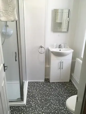a white bathroom with a sink and a shower at Hilbre Hotel in Blackpool