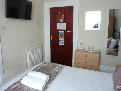 a bedroom with a bed and a red door at Hilbre Hotel in Blackpool