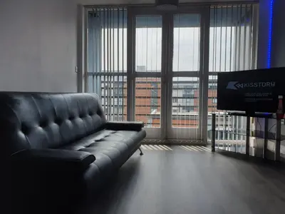 a living room with a leather couch and a television at Shandon Apt premium Liverpool City Centre in Liverpool