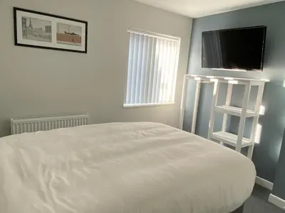a bedroom with a white bed and a flat screen tv at Brownlows Inn Rooms formerly Riley's Rooms in Liverpool