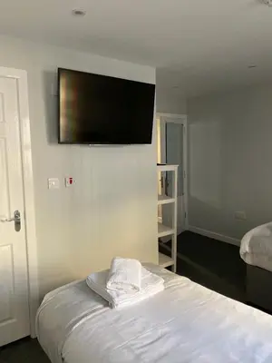 a room with a bed and a flat screen tv on the wall at Brownlows Inn Rooms formerly Riley's Rooms in Liverpool