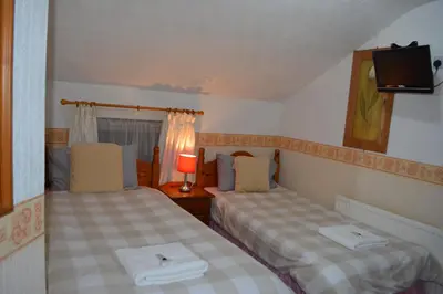 a bedroom with two beds and a tv on the wall at BLACKPOOL MERCY Inn HOTEL in Blackpool