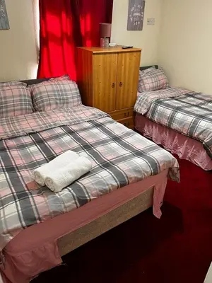 a room with two beds and a dresser at BLACKPOOL MERCY Inn HOTEL in Blackpool