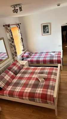 two beds in a bedroom with a plaid bedspread at Fairhaven Hotel on Woodfield Road in Blackpool