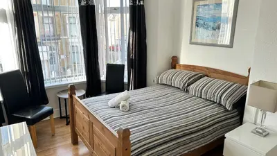 a bedroom with a bed and two chairs and a window at Fairhaven Hotel on Woodfield Road in Blackpool