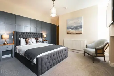 a bedroom with a large bed and a chair at Rooms at The Dressers Arms in Chorley