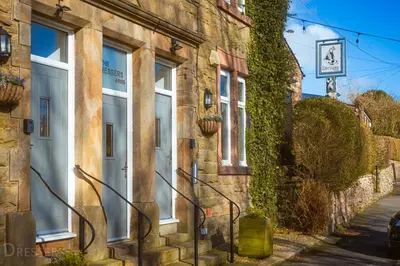 a stone building with white windows and ivy at Rooms at The Dressers Arms in Chorley