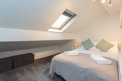 a attic bedroom with a bed and a window at Cherry Property - Apple Suite in Blackpool