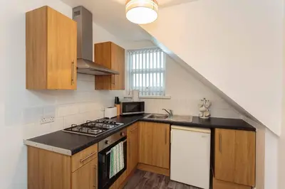 a kitchen with wooden cabinets and a stove top oven at Cherry Property - Apple Suite in Blackpool