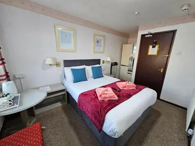 a hotel room with a large bed and a table at Collingwood Hotel in Blackpool