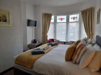 a bedroom with a large white bed with windows at Collingwood Hotel in Blackpool