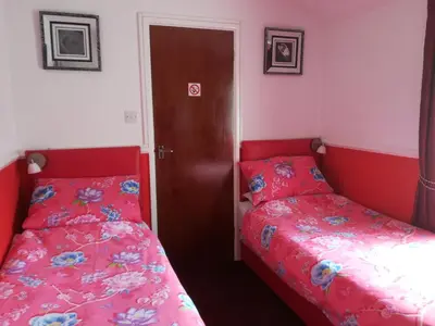 two beds in a room with red and white walls at Delamere Hotel in Blackpool