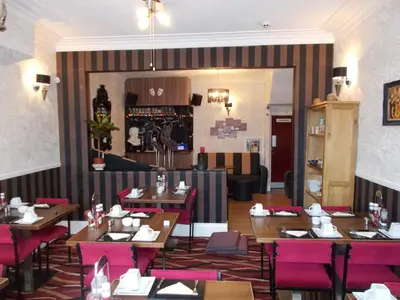 a restaurant with wooden tables and pink chairs at Delamere Hotel in Blackpool