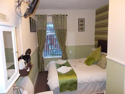 a small room with a bed and a window at Delamere Hotel in Blackpool