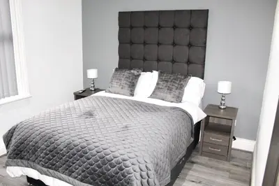 a bedroom with a large bed with a large headboard at Reads Jacuzzi Apartments in Blackpool