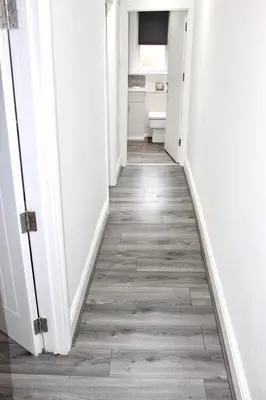 a hallway with white walls and wooden floors at Reads Jacuzzi Apartments in Blackpool