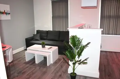 a living room with a black couch and a table at Reads Jacuzzi Apartments in Blackpool