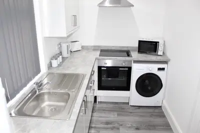 a kitchen with a sink and a washing machine at Reads Jacuzzi Apartments in Blackpool
