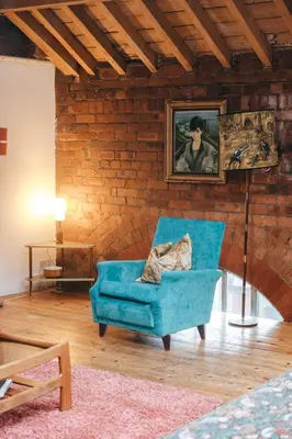 a living room with a blue chair and a painting at Loftnine9 in Liverpool