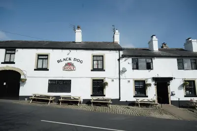 a white building with picnic tables in front of it at Black Dog Inn in Bolton