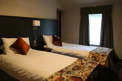 a hotel room with two beds and a window at Black Dog Inn in Bolton