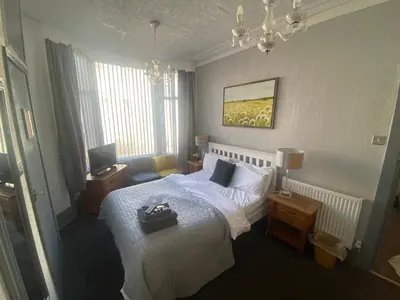 a bedroom with a white bed and a chandelier at Bradburys of Blackpool in Blackpool