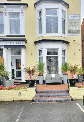 a yellow house with a bench in front of it at The Copplehouse in Southport