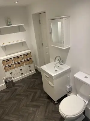 a white bathroom with a toilet and a sink at Beach House Courtyard 1 bed in Southport
