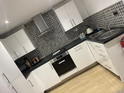 a white kitchen with white cabinets and a sink at Beach House Courtyard 1 bed in Southport
