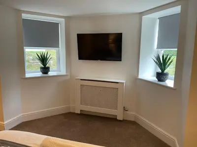 a living room with two windows and a flat screen tv at Beach House Courtyard 1 bed in Southport