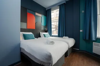 two beds in a room with blue walls and a window at Kabannas Liverpool in Liverpool
