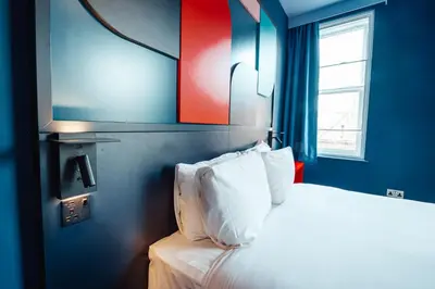 a bedroom with a bed with white pillows and a window at Kabannas Liverpool in Liverpool