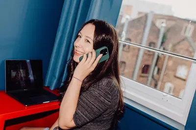 a woman talking on a cell phone in front of a window at Kabannas Liverpool in Liverpool
